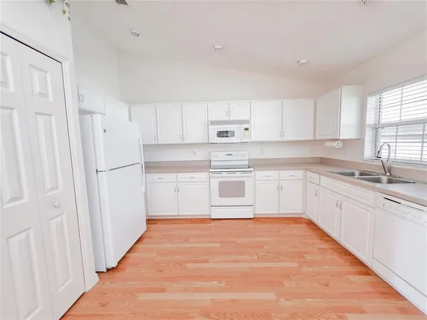 a white kitchen with granite top and stainless steel appliances
