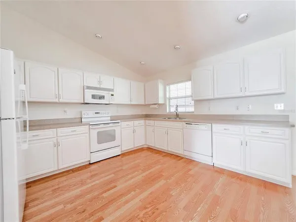 a kitchen with cabinets appliances a sink and a window