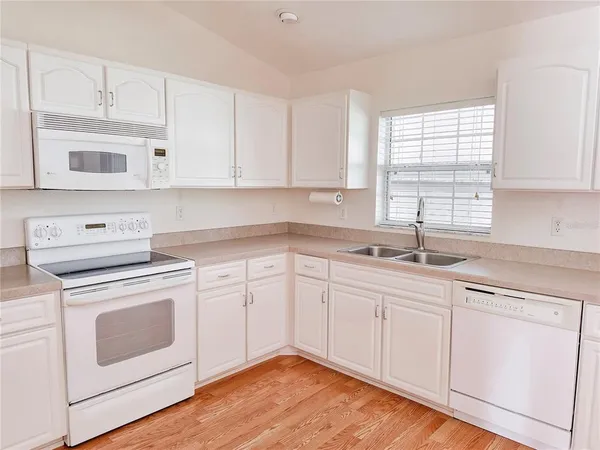 a view of a kitchen with wooden floor and electronic appliances