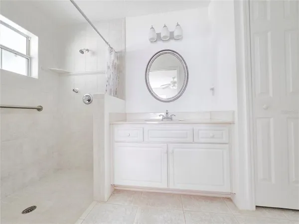 an empty room with chandelier fan and windows