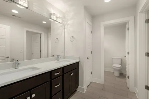 a bathroom with a granite countertop sink a toilet and a large mirror