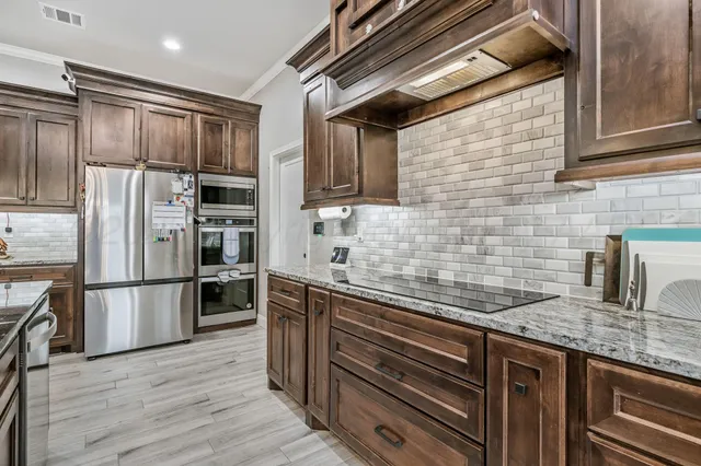 a kitchen with granite countertop stainless steel appliances and wooden cabinets
