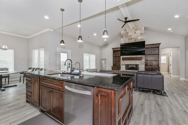 a kitchen with kitchen island granite countertop a stove a sink a refrigerator dining table and chairs with wooden floor