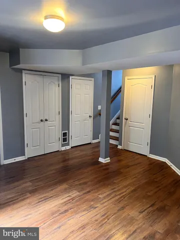 an empty room with wooden floor closet and windows