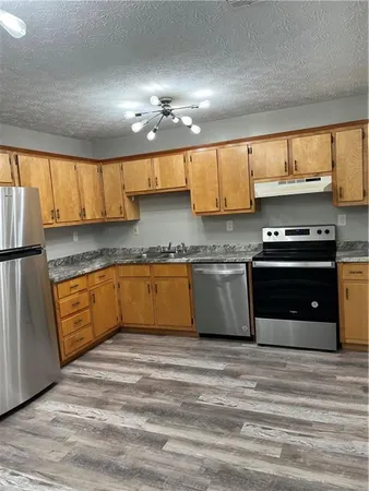 a kitchen with granite countertop a sink cabinets and stainless steel appliances