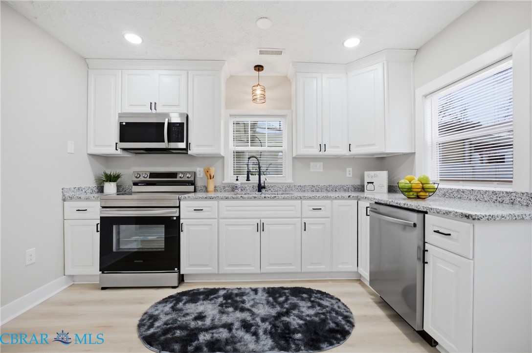 733 Spruce Street Hampton, VA 23661 - Photo 10 of 29 Kitchen with stainless steel appliances, white cabinetry, light wood-style floors, and light stone counters