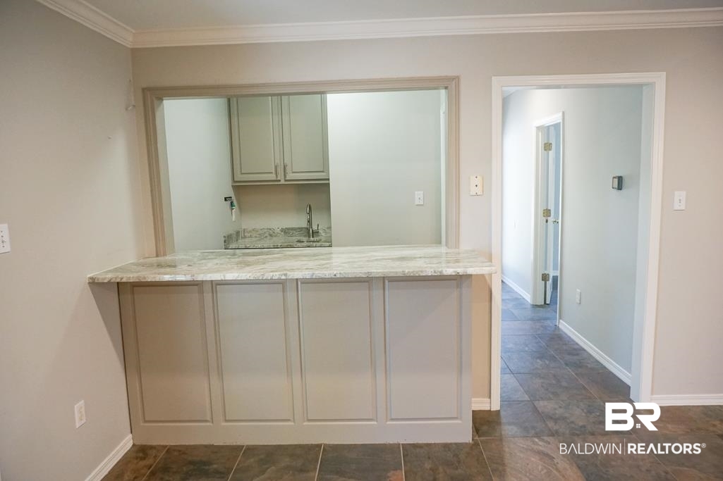 255 Suffolk Road Mobile, AL 36608 - Photo 19 of 29 Kitchen with crown molding, light stone countertops, and a peninsula
