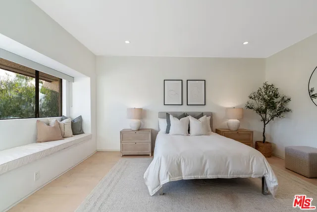 a bedroom with a large bed couch and a potted plant