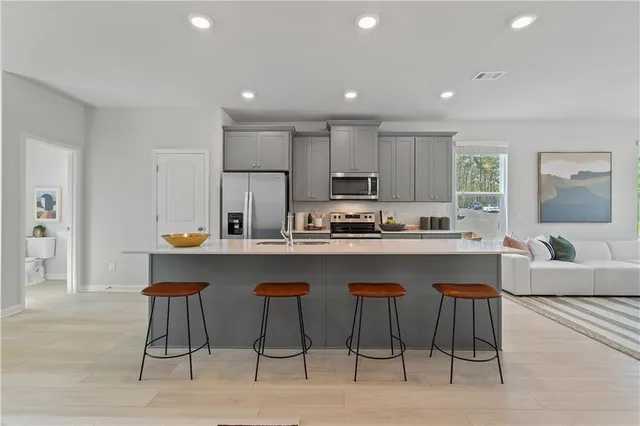 a kitchen with stainless steel appliances granite countertop a stove a sink a refrigerator and white cabinets with wooden floor