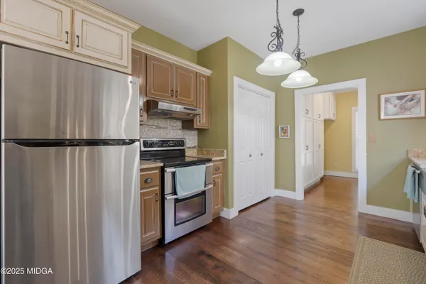 a kitchen with stainless steel appliances granite countertop a refrigerator a stove and a wooden floors