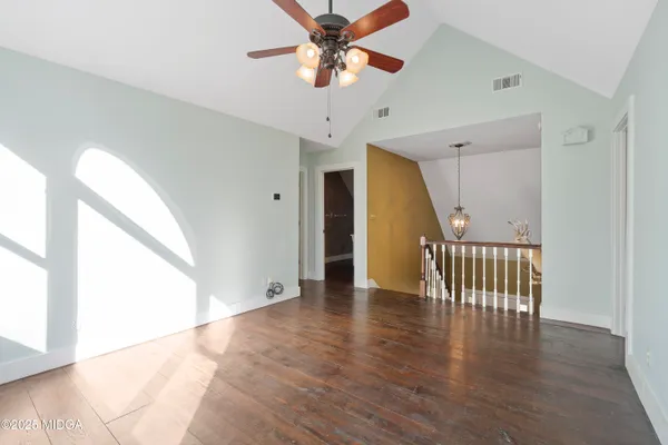 a view of an empty room with window and wooden floor