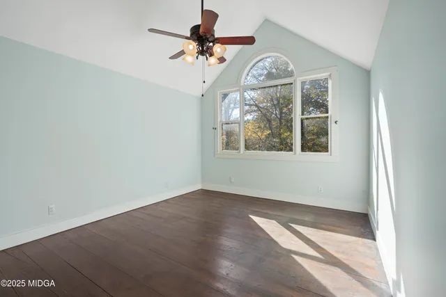 an empty room with a chandelier fan and windows
