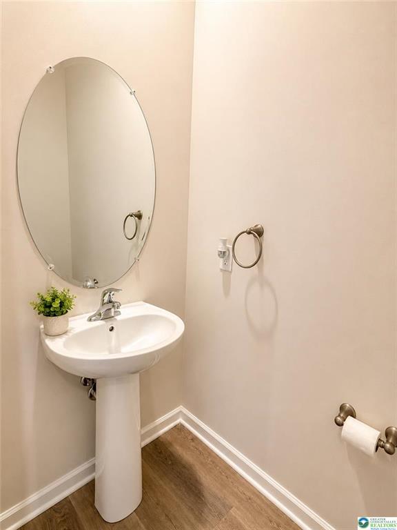 A classic pedestal sink pairs with warm wood-look flooring in this tidy half bath.