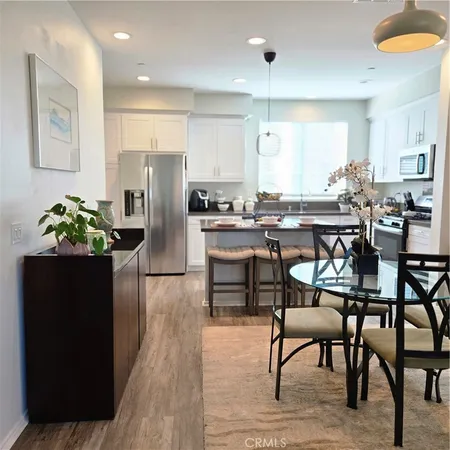 a kitchen with stainless steel appliances granite countertop table chairs refrigerator and microwave