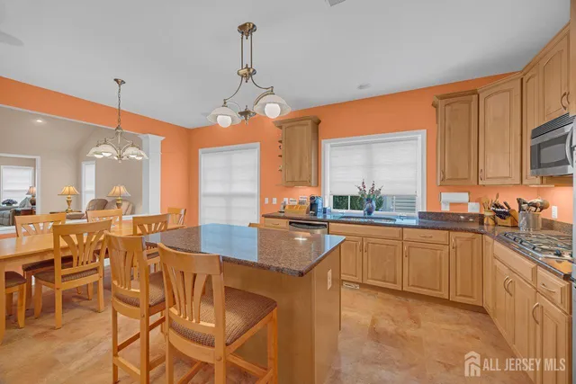 a kitchen with stainless steel appliances granite countertop wooden cabinets a stove a sink a dining table and chairs