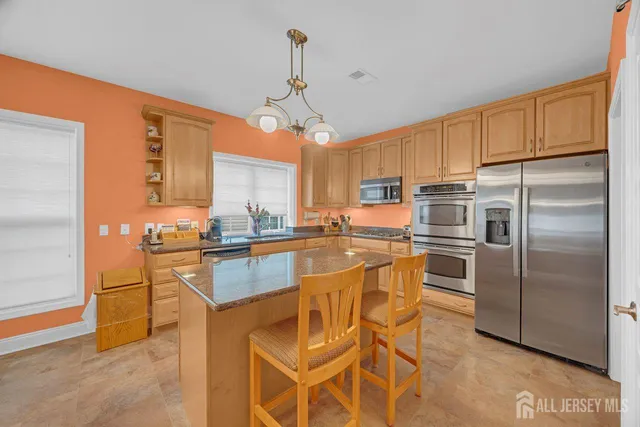 a kitchen with stainless steel appliances granite countertop a refrigerator a stove a sink and white cabinets