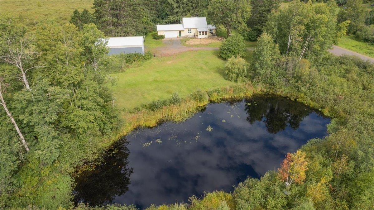 Aerial view of property and surrounding area with a large body of water and a heavily wooded area