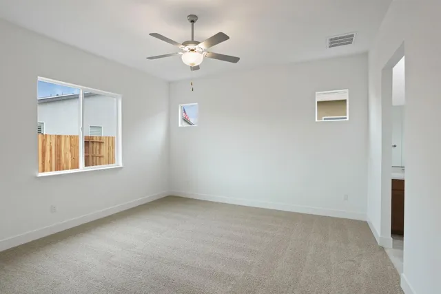 an empty room with windows and fan