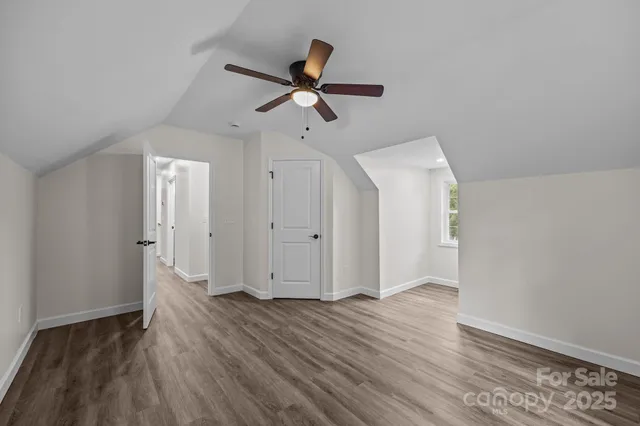 an empty room with wooden floor cabinet and windows
