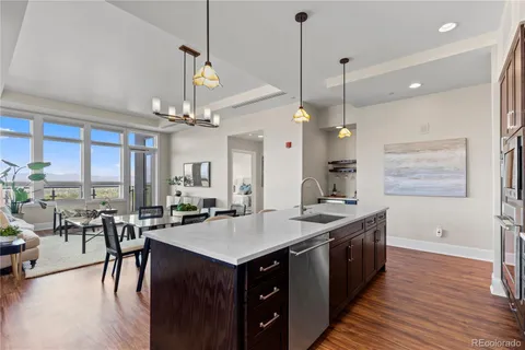 a kitchen with center island a sink dishwasher a dining table and chairs with wooden floor