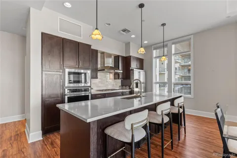 a kitchen with kitchen island a large counter top space appliances and wooden floor