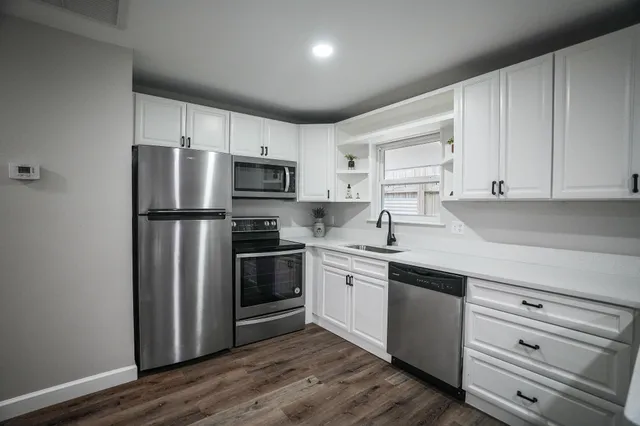 a kitchen with stainless steel appliances a sink cabinets and wooden floor
