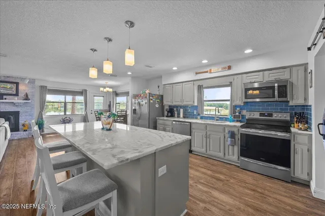 a kitchen with stainless steel appliances granite countertop a stove top oven a sink dishwasher a dining table and chairs with wooden floor