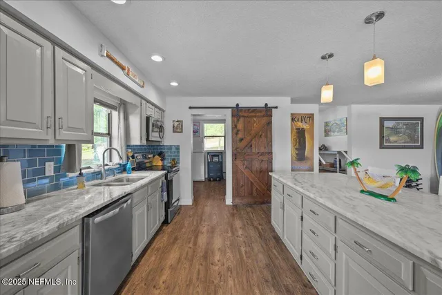 a large kitchen with stainless steel appliances granite countertop a lot of counter space and wooden floors