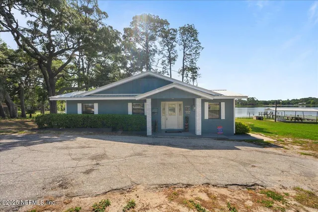 a front view of a house with a yard and lake view