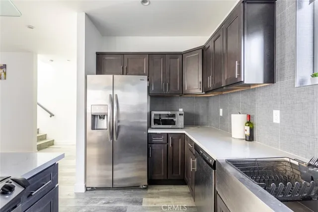 a kitchen with stainless steel appliances granite countertop a refrigerator a stove and a sink with wooden cabinets