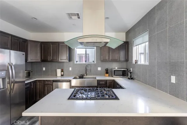 a kitchen with stainless steel appliances granite countertop a sink a stove a refrigerator cabinets and a window