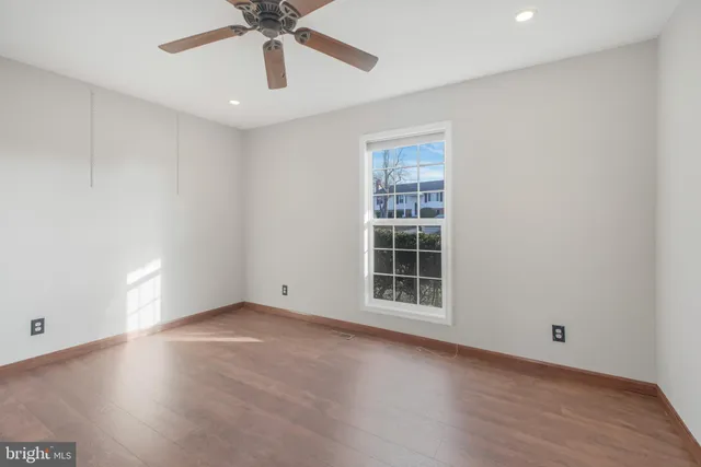 an empty room with wooden floor chandelier fan and windows