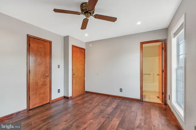 an empty room with wooden floor cabinet and windows