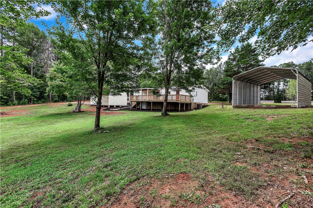403 Hancox Place Westminster, SC 29693 - Photo 9 of 39 A spacious backyard with mature trees, an expansive deck, and a detached carport.