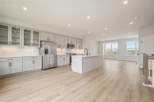 a living room with kitchen island wooden floor and white appliances