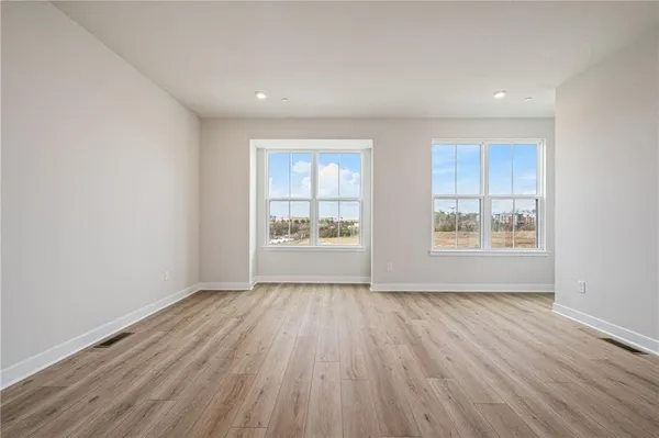 a view of an empty room with a window and wooden floor
