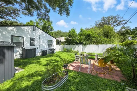 a backyard of a house with table and chairs plants and large tree