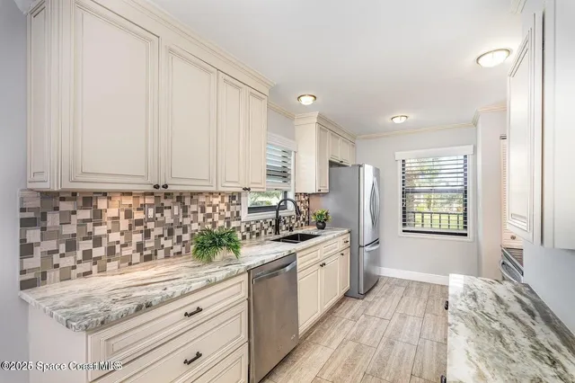 a kitchen with granite countertop a sink stainless steel appliances white cabinets and wooden floor