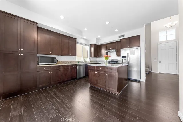 a kitchen with stainless steel appliances a sink a counter top space cabinets and wooden floor