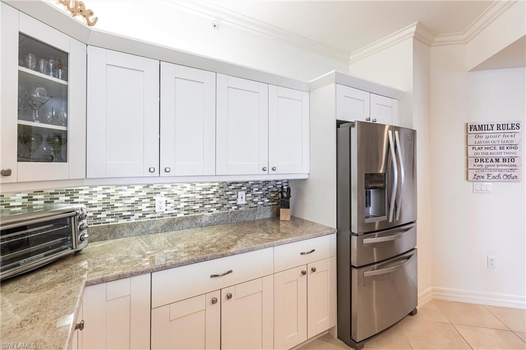 451 Bayfront Place, Unit 5309 Naples, FL 34102 - Photo 11 of 33 Kitchen with stainless steel fridge with ice dispenser, crown molding, white cabinetry, glass insert cabinets, and light tile patterned floors