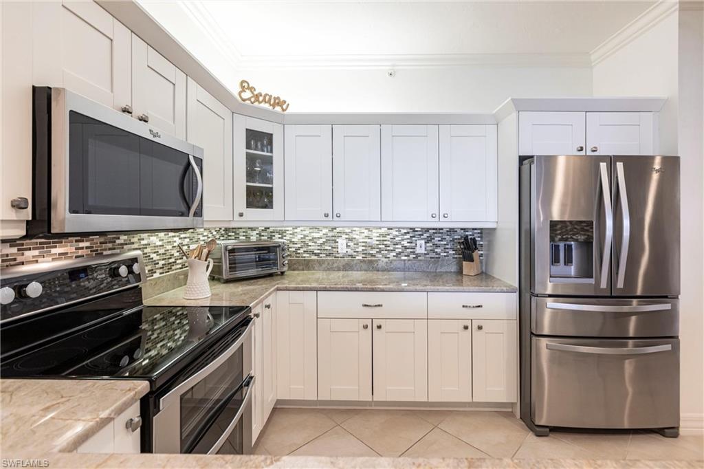 451 Bayfront Place, Unit 5309 Naples, FL 34102 - Photo 12 of 33 Kitchen with appliances with stainless steel finishes, ornamental molding, decorative backsplash, white cabinets, and light tile patterned floors