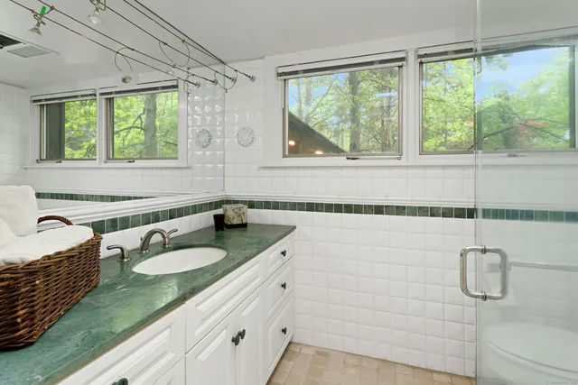 a bathroom with a granite countertop sink and a large mirror next to a window