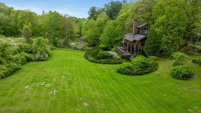 a view of a backyard with table and chairs plants and large trees