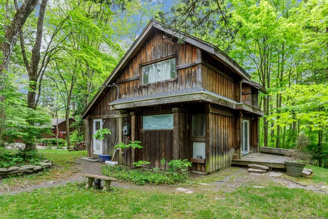 a view of brick house with a yard and large trees