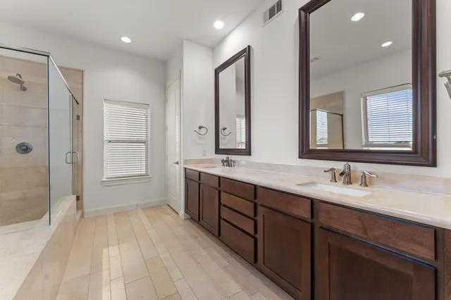 a spacious bathroom with a double vanity sink a large mirror and a shower