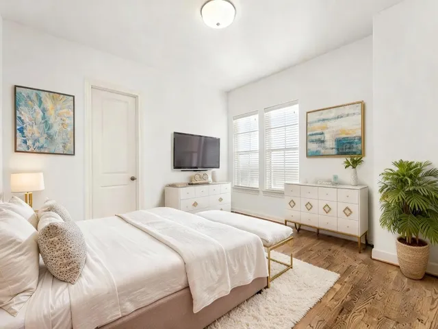 a bedroom with a large bed and a flat tv screen on dresser