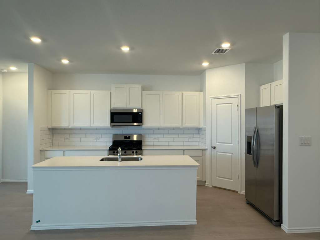 577 Sormonne Loop Kyle, TX 78640 - Photo 9 of 39 a kitchen with stainless steel appliances granite countertop a refrigerator a sink and white cabinets