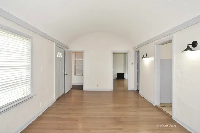 a view of an empty room with wooden floor and a window