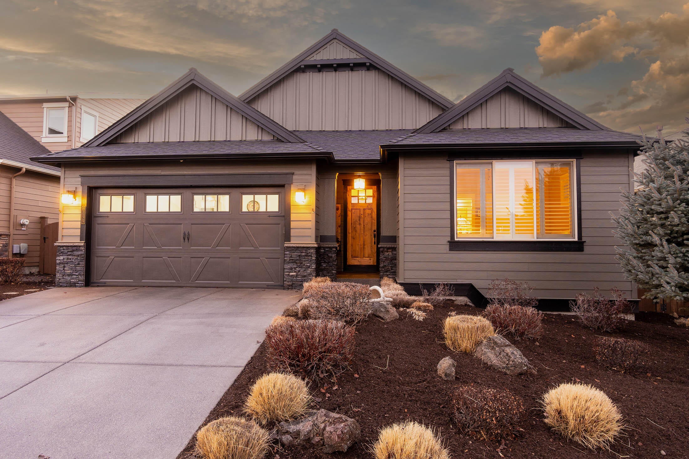 61129 Manhae Loop Bend, OR 97702 - Photo 2 of 44 Front exterior has stone masonry accents and exposed aggregate driveway and walk to covered front porch. Eastern facing, offering opportunity for sun exposure & warmth on cool mornings.