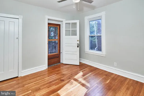 an empty room with wooden floor chandelier and windows